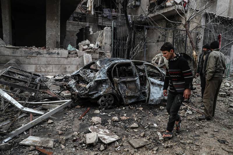 This photo, taken on January 6, 2016, shows a boy walking past a destroyed car in Eastern Ghouta's Hammuriyeh, where at least 12 civilians were killed. Mohammed Badra / EPA