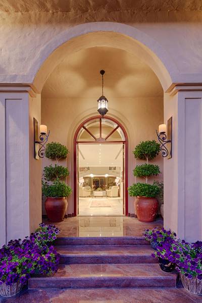 The curved entrance went against the client's first love of lines, but the designer brought it into place with symmetrical planting. The dramatic entrance lighting with precision-cut foliage also sets an inviting scene