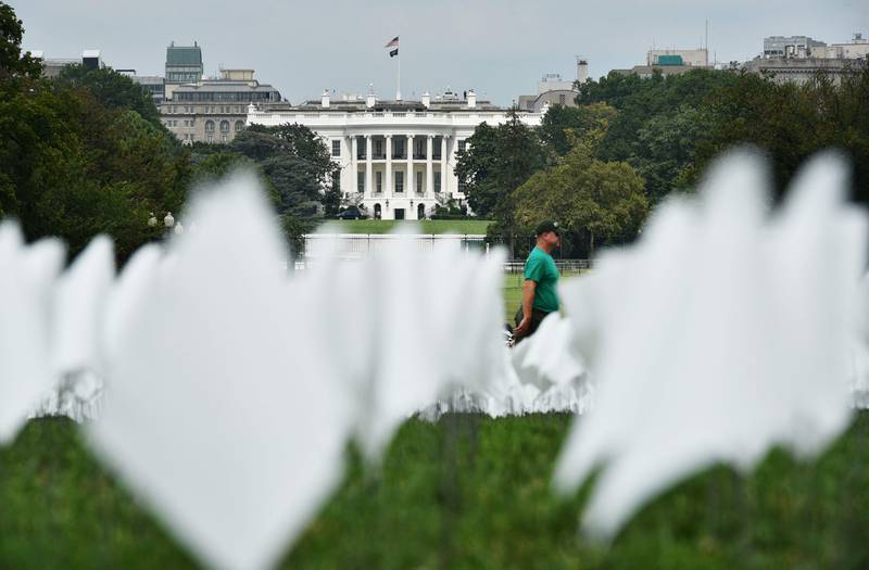 The White House is seen behind a field of white flags on the Mall, near the Washington Monument in Washington, DC on September 16, 2021.  - The project, by artist Suzanne Brennan Firstenberg, uses over 600,00 miniature white flags to symbolize the lives lost to Covid-19 in the US.  (Photo by MANDEL NGAN  /  AFP)