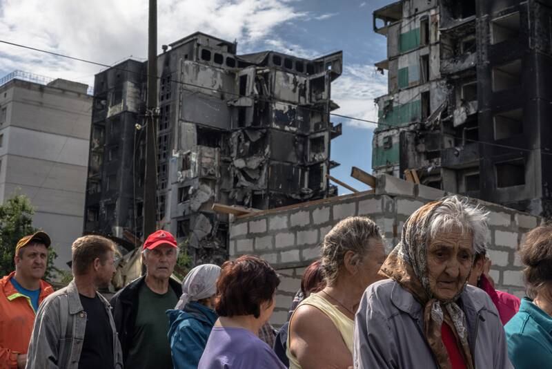 People wait to receive humanitarian aid in front of a residential building damaged during a Russian attack in Borodyanka, Ukraine. EPA