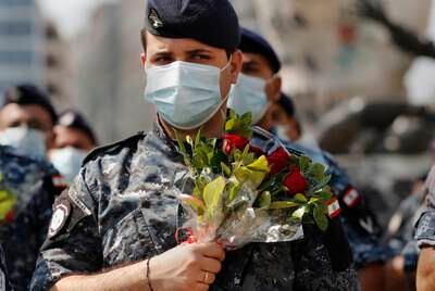 Police hold flowers to mark the anniversary of Beirut's massive 2020 port blast.