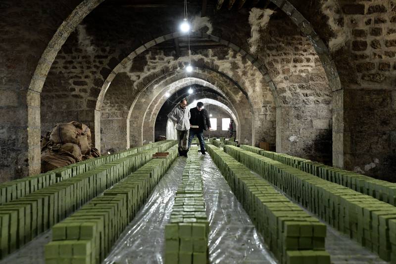 Workers inspect stacks of laurel soap at the Jbaili soap factory, an 800 year old artisan manufacturer, in the old city of Aleppo. The plant, heavily damaged during the civil war, has been renovated and resumed operations after Syrian government forces regained control of the old city. AFP