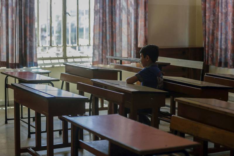 A Lebanese pupil looks out of the window as he sits in his empty classroom after coming to collect the books he left before the COVID-19 lockdown, at Our Lady of Lourdes school in the Lebanese city of Zahle, in the central Bekaa region, on June 30, 2020. - Until recently, Lebanon's French-speaking schools, a large majority Catholic, taught 500,000 children -- equivalent to around half of all pupils nationwide. But the country's worst economic crisis since the 1975-1990 civil war has left them battling to stay afloat as parents struggle to pay fees, and put French-language education in jeopardy. (Photo by JOSEPH EID / AFP)