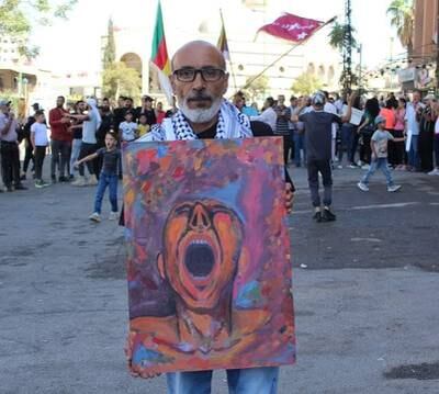 Syrian painter and former political prisoner Suhail Thebian holding a painting by a fellow artist, at a demonstration in the south-western governorate of Suweida. Photo: Suhail Thubian