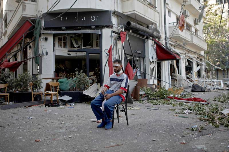 An injured man sits next to a restaurant in the trendy partially destroyed Beirut neighbourhood of Mar Mikhael.  AFP