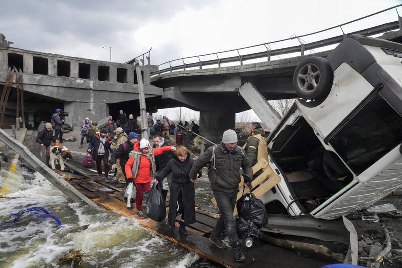 People pass a damaged bridge while fleeing the town of Irpin, close to the Ukrainian capital of Kyiv. AP