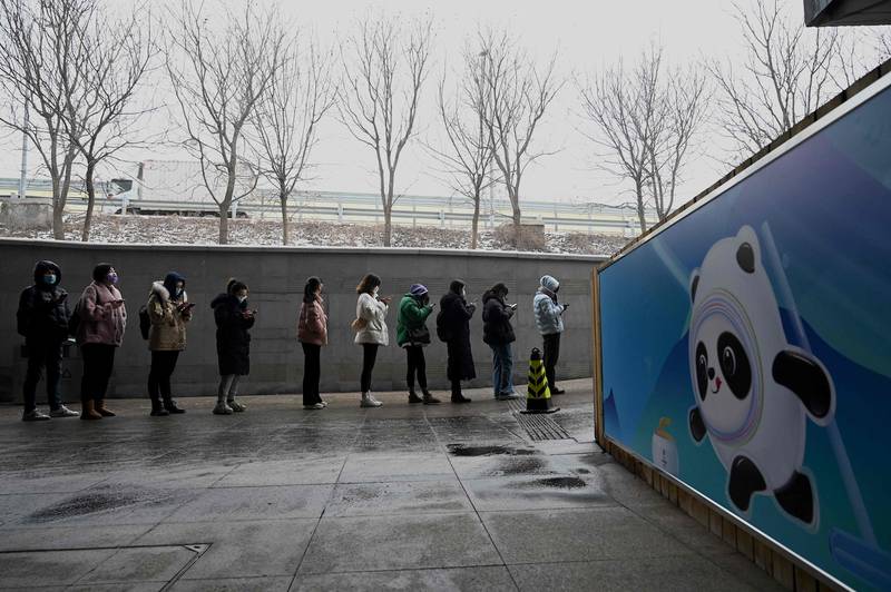 People queue next to a poster of Bing Dwen Dwen, the mascot of the Beijing 2022 Winter Olympics, to have their swab samples taken to test for the Covid-19 coronavirus in Beijing, China. AFP