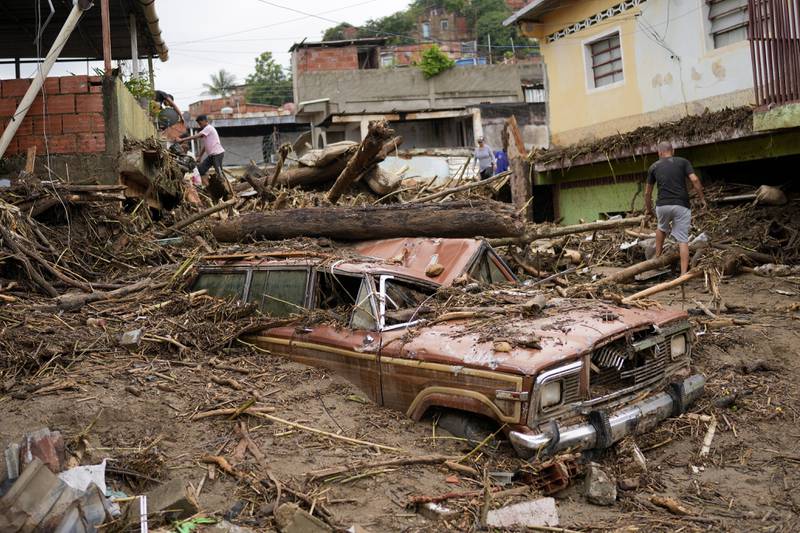 Residents walk through the debris left by flooding caused by a river that overflowed in Las Tejerias, Venezuela, on October 9, 2022. AP Photo