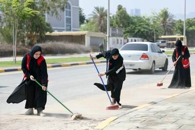 Volunteers from the community service group Takatof sweep debris from a road, after the floods in Fujairah. Khushnum Bhandari / The National
