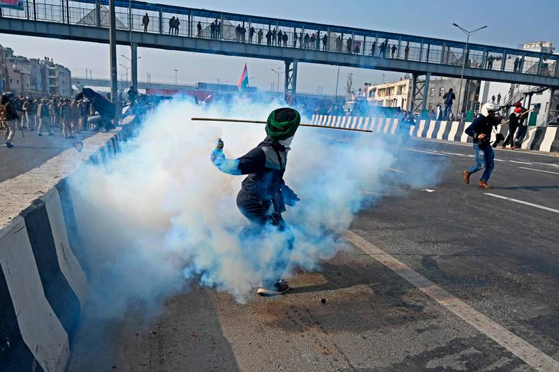 A farmer throws back a tear gas shell towards police during a tractor rally as farmers continue to protest against the central government's recent agricultural reforms in New Delhi. AFP