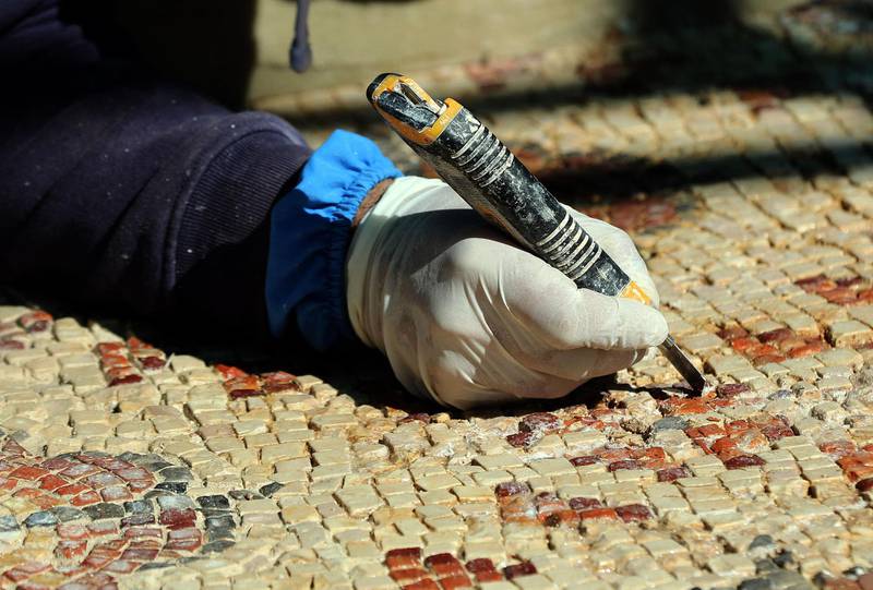 A worker undertakes the painstaking process of restoring a mosaic floor at the ancient church complex, in Rihab, Jordan. AFP