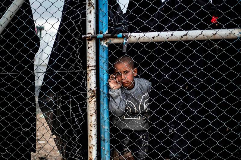 A child waits behind a wire fence door in al-Hol camp, which houses relatives of Islamic State (IS) group members, in al-Hasakeh governorate in northeastern Syria on March 28, 2019.  / AFP / Delil SOULEIMAN
