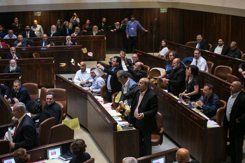 Arab lawmakers stand up in protest during a Knesset session in Jerusalem, Thursday, July 19, 2018. Israel's parliament approved a controversial piece of legislation on Thursday that defines the country as the nation-state of the Jewish people but which critics warn sidelines minorities. (AP Photo/Olivier Fitoussi)