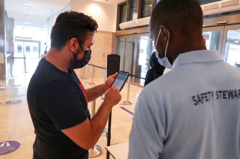 A man shows the green pass on his phone before entering a shopping mall in Abu Dhabi, UAE. Khushnum Bhandari / The National