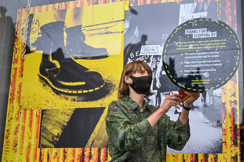 EDINBURGH, SCOTLAND - JUNE 29: A member of staff applies a safety sign to the Dr Martens store window in Princess Street as the Scottish Lockdown eases and shops reopen on June 29, 2020 in Edinburgh, Scotland. Shops with on-street access opened their doors as non-essential retailers across Scotland were allowed trade again. (Photo by Jeff J Mitchell/Getty Images)