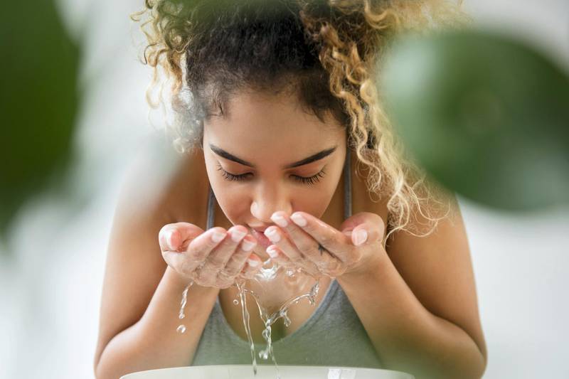Mixed Race woman splashing water on face