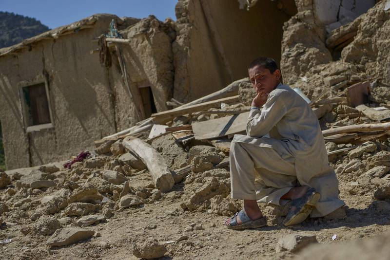 An Afghan youth sits besides the ruins of damaged houses. AFP