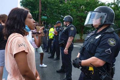 Protesters stand in front of police in Atlanta. AP