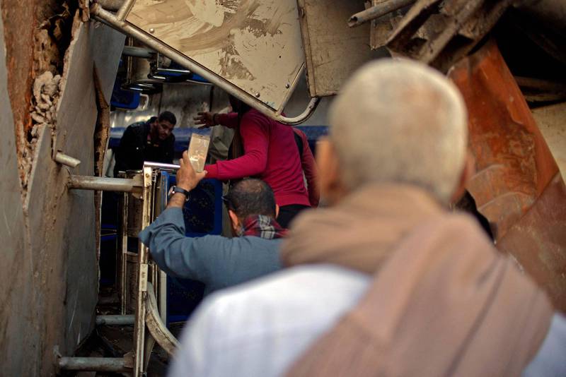 People gather around the wreckage of two trains that collided in the Tahta district of Sohag province, some 460 kms (285 miles) south of the Egyptian capital Cairo. AFP