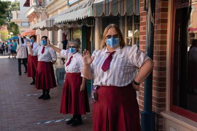 Restaurant workers greet returning guests on Main Street USA during the reopening of the Disneyland theme park in Anaheim, California, U.S., on Friday, April 29, 2021. Walt Disney Co.'s original Disneyland resort in California is sold out for weekends through May, an indication of pent-up demand for leisure activities as the pandemic eases in the nation's most-populous state. Photographer: Bing Guan/Bloomberg