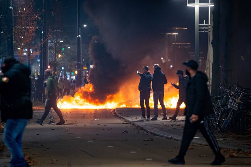 People stand near burning objects after a protest against the '2G policy' turned into riots. EPA