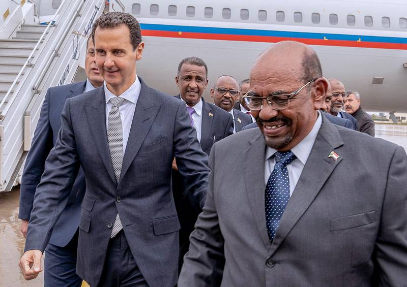 epa07236362 A handout photo made available by Syrian Arab news agency SANA shows Syrian  President Bashar al-Assad (L) receive the President of Sudan Omar Hassan al-Bashir (R) at Damascus international airport in Damascus, Syria, 16 December 2018. President of Sudan Omar Hassan al-Bashir arrived on Sunday afternoon at Damascus International Airport for an official visit. Afterwards, President al-Assad and President al-Bashir headed to the People’s Palace, where they held a session of talks on bilateral relations and developments in Syria and the region.  EPA/SANA HANDOUT  HANDOUT EDITORIAL USE ONLY/NO SALES