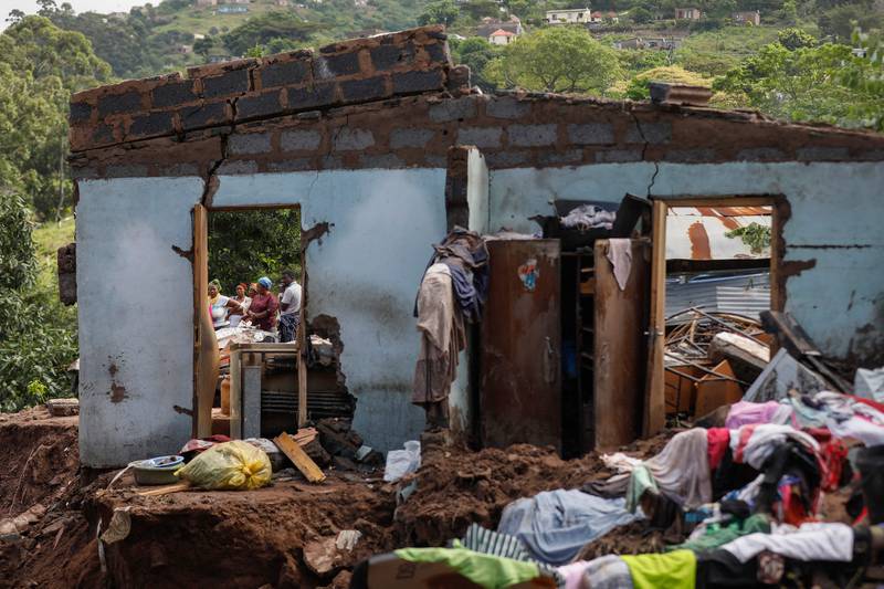 Neighbours stand next to the remains of a house at KwaNdengezi township outside Durban, where 10 people are reportedly missing after their homes were swept away following devastating rains and flooding. AFP