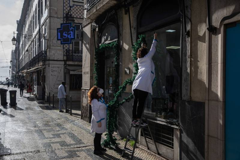 Pharmacy workers remove Christmas decorations from a window in Lisbon, Portugal. While Portugal has been reporting record figures of daily new coronavirus cases driven by the Omicron variant, the number of patients in intensive-care units has fallen. Bloomberg