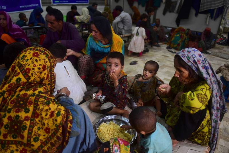 Displaced people eat food provided by Saylani Welfare in Sukkur. AFP