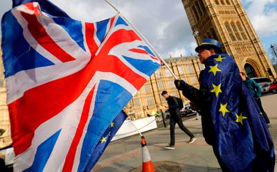 An anti-Brexit demonstrator waves a Union flag as he stands draped in a European Union (EU) flag outside the Houses of Parliament in London on March 28, 2018.
With Britain just a year away from leaving the European Union, the transition deal agreed between the two sides is viewed as a key element to absorbing the Brexit shock. British Prime Minister Theresa May kick-started divorce proceedings one year ago, and March 29, 2019, has since been set as the date the UK will leave the bloc. / AFP PHOTO / Tolga AKMEN