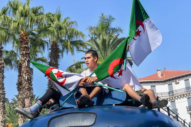 Youths hold Algerian flags as they sit on top of a bus during celebrations to mark the anniversary of the revolution. AFP