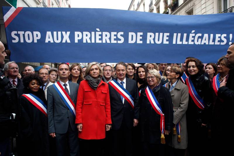 Clichy la Garenne's mayor Remi Muzueau, center right, and President of the Regional Council of the Ile-de-France region Valerie Pecresse, center left, demonstrate against Muslim street prayers, in the Paris suburb of Clichy la Garenne, Friday, Nov. 10, 2017. Tensions have erupted as residents and the mayor of a Paris suburb tried to block the town's Muslims from praying in the street in a dispute that reflects nationwide problems over mosque shortages. Banner reads "Stop to the Illegals Prayers". (AP Photo/Thibault Camus)