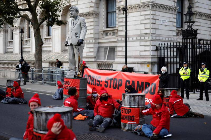 Greenpeace activists surround the statue of Boris Johnson as they stage their sit-in protest. AFP