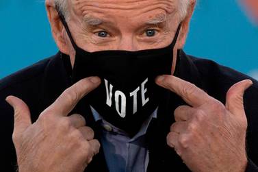 TOPSHOT - US President-elect Joe Biden points to his face mask with the word "Vote" printed on it during a rally outside Center Parc Stadium in Atlanta, Georgia, on January 4, 2021. President Donald Trump, still seeking ways to reverse his election defeat, and President-elect Joe Biden converge on Georgia on Monday for dueling rallies on the eve of runoff votes that will decide control of the US Senate. Trump, a day after the release of a bombshell recording in which he pressures Georgia officials to overturn his November 3 election loss in the southern state, is to hold a rally in the northwest city of Dalton in support of Republican incumbent senators Kelly Loeffler and David Perdue. Biden, who takes over the White House on January 20, is to campaign in Atlanta, the Georgia capital, for the Democratic challengers, Raphael Warnock and Jon Ossoff. / AFP / JIM WATSON
