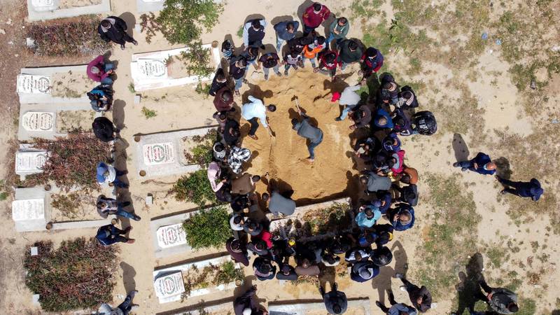 A picture taken with a drone shows Palestinians burying the body of a man, who died after contracting the coronavirus disease (COVID-19), at a cemetery in the central Gaza Strip April 6, 2021. REUTERS/Mohammed Salem