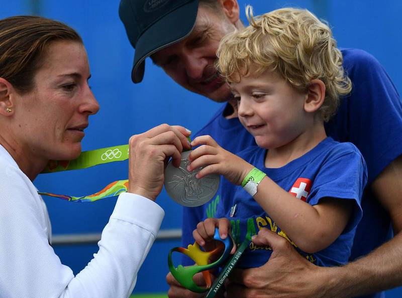 Switzerland’s Nicola Spirig (L) shows her silver medal to her family after the women’s triathlon at Fort Copacabana during the Rio 2016 Olympic Games in Rio de Janeiro on August 20, 2016. Leon Neal / AFP