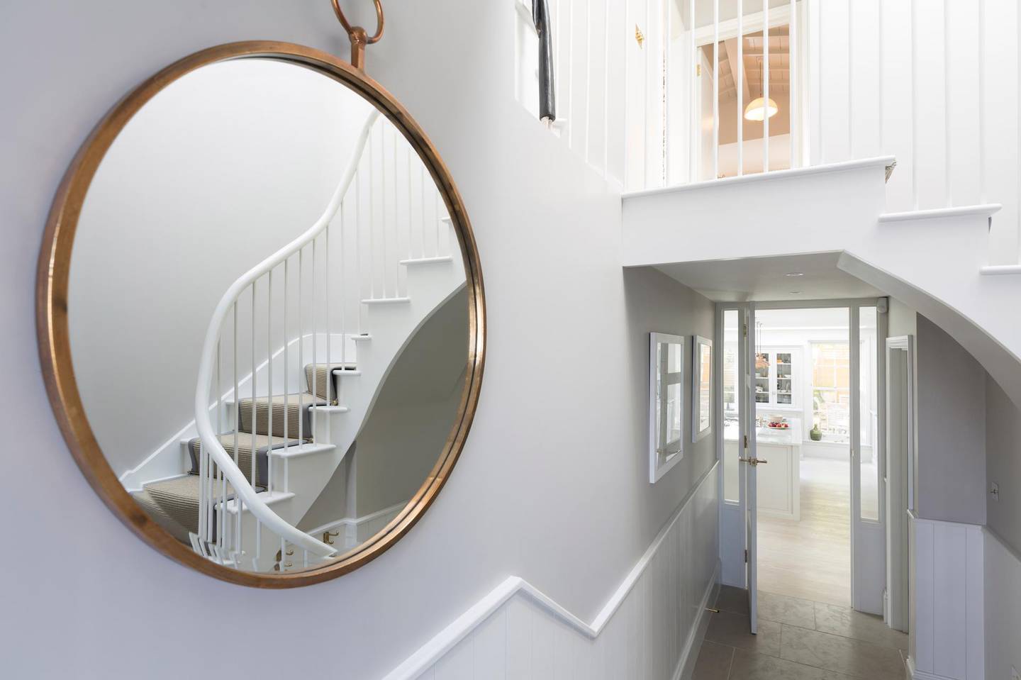 Reflection of foyer staircase in round mirror. Getty Images