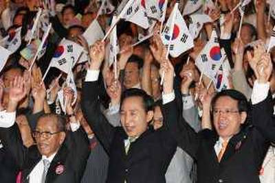 South Korean President Lee Myung-bak, center, and attendants with national flags cheer during a ceremony to celebrate Korean Liberation Day from Japanese colonial rule in 1945, in Seoul, South Korea, Saturday, Aug. 15, 2009. Lee Saturday renewed his offer to provide aid to North Korea if the regime gives up its nuclear weapons program, two days after Pyongyang freed a detained southern worker in an apparent conciliatory gesture amid tension on its bombs program.(AP Photo/Yonhap, Chun Soo-young)  **KOREA OUT** *** Local Caption ***  SEL801_South_Korea_Koreas_Tension.jpg