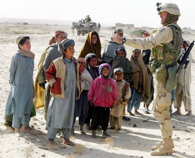 400626 06: 101st Airbornes 1st Sgt. Kerry Black from Westmoreland, Tennessee uses an Afghan childs sling shot February 6, 2002 as children crowd around him while he patrols on the outskirts of Kandahar, Afghanistan. The soldiers were on a reconnaissance and security patrol as well as looking for hidden ordinances. (Photo by Joe Raedle/Getty Images)