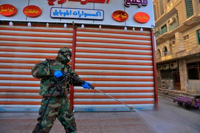 A Civil Defense member wearing protective suits sprays disinfectant as a precaution against the coronavirus in the closed shops, and hotels in Najaf, Iraq.  AP