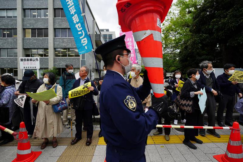 A police officer holds traffic cones as people protest against government's decision to start releasing massive amounts of treated radioactive water from the wrecked Fukushima nuclear plant into the sea. AP