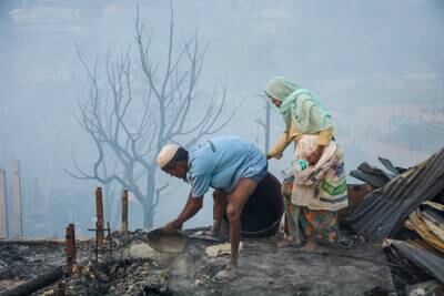 Refugees rummage through the smouldering ruins as they look for items they can salvage. EPA