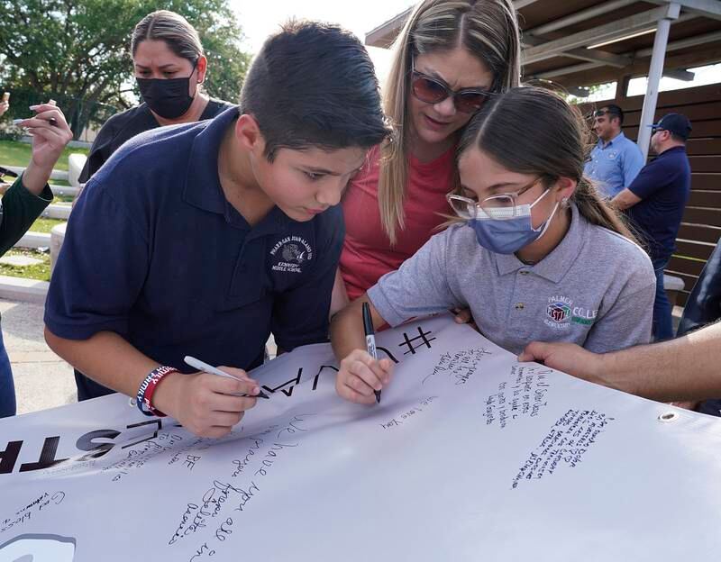 Omahar Padillo Jr, 12, and his sister Samantha, 9, with their mother, Silvia Padillo, write messages in support of the victims at Robb Elementary School.  AP
