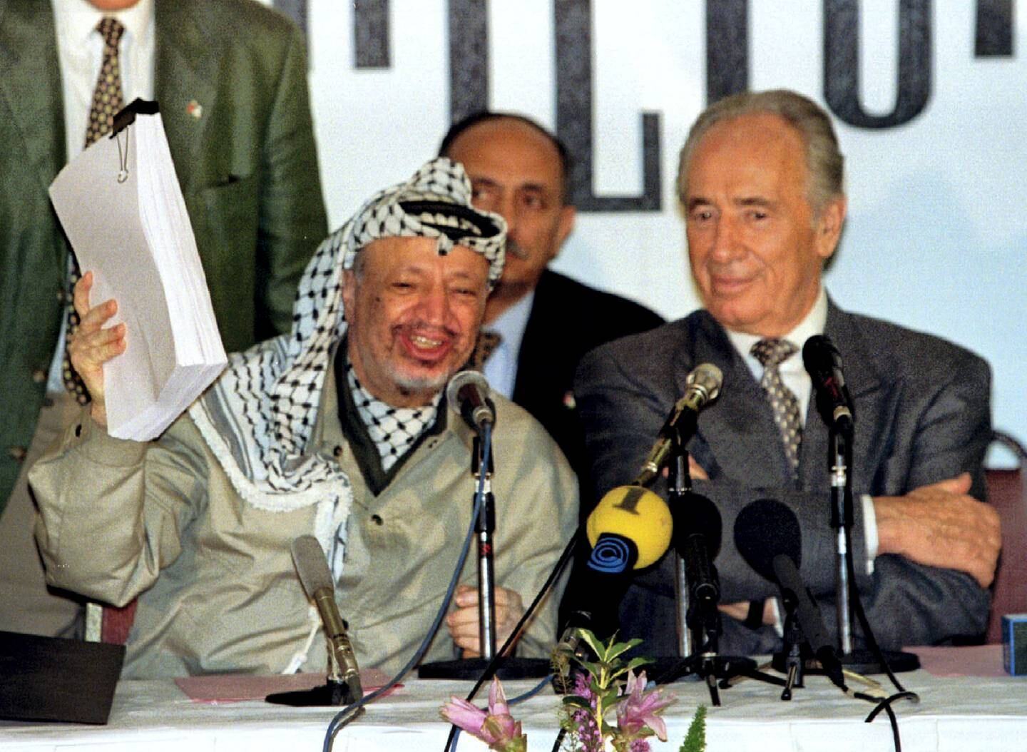 PLO chairman Yasser Arafat holds the second phase of the Oslo peace accords after the initialling of the document, September 24, as Israeli Foreign Minister Shimon Peres looks on. Israel and the PLO will officially sign the agreement in Washington later this week.
**POOR QUALITY DOCUMENT