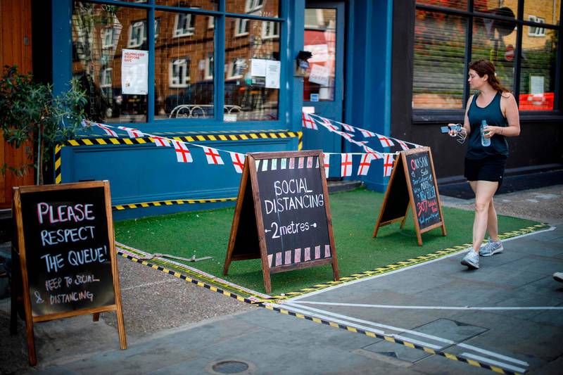 A woman walks past a restaurant with social distancing markings in Portobello Market in west London, following the easing of the lockdown restrictions during the novel coronavirus pandemic.  AFP