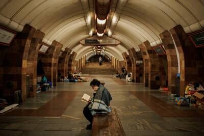 A woman reads as residents shelter from Russian shelling in a Kharkiv metro station. Reuters