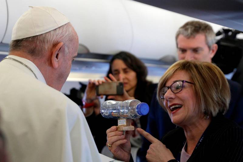 Pope Francis is given a plastic bottle containing a ship made by inmates of a Spanish prison by Spanish journalist Eva Fernandez aboard the Pope's plane. AFP