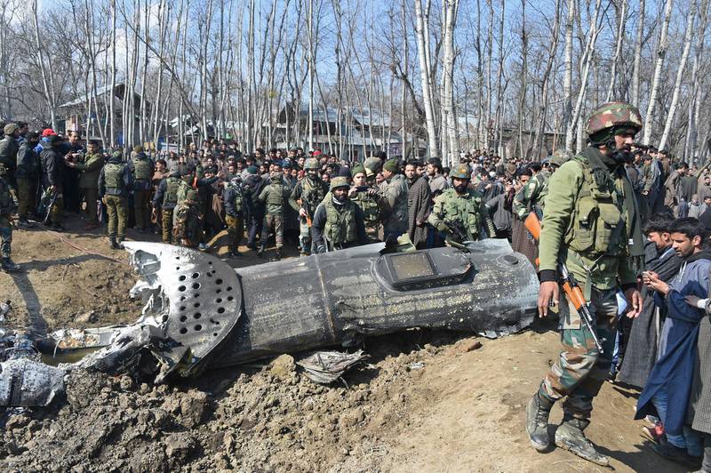 Indian soldiers and Kashmiri onlookers stand near the remains of an Indian Air Force aircraft after it crashed in Budgam district, 30 km from Srinagar. AFP