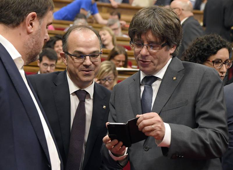 (FILES) In this file photo taken on September 6, 2017 Catalan regional president Carles Puigdemont (R) shows his mobile phone to the leader of Junts Pel Si (Together for Yes), Jordi Turull (C) beside Catalan regional vice-president and chief of Economy and Finance, Oriol Junqueras during a session recess at the Catalan parliament in Barcelona.
Spain's Telecinco television channel revealed on January 31, 2018 a series of mobile phone messages written by sacked Catalan leader Carles Puigdemont to another separatist, in which he says it's likely all over for him.

 / AFP PHOTO / LLUIS GENE