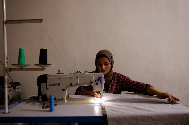 Noor Al Janabi sews fabric for furniture at her home in Baghdad.
